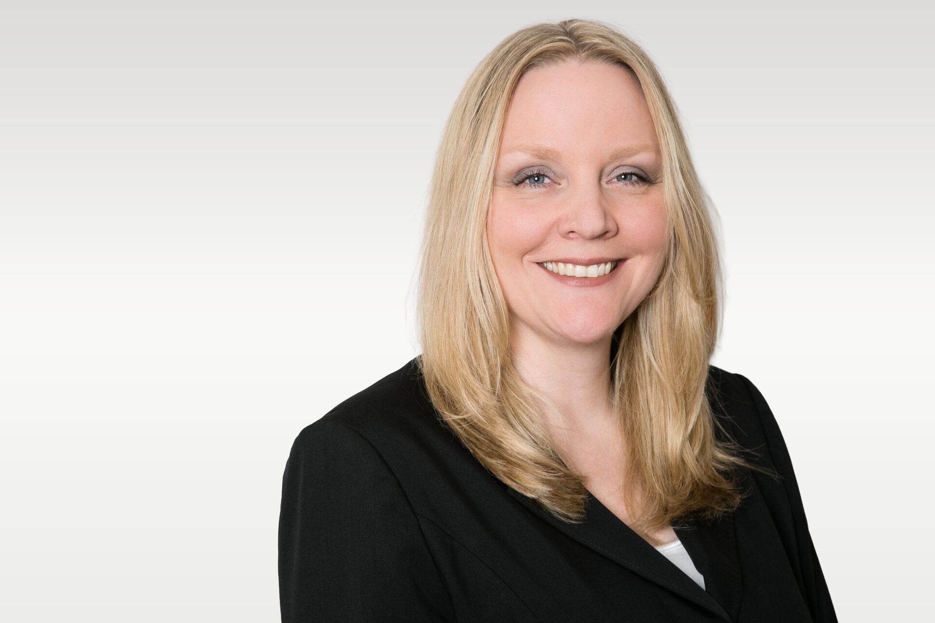 Lächelnde blonde Frau im schwarzen Blazer, Porträt